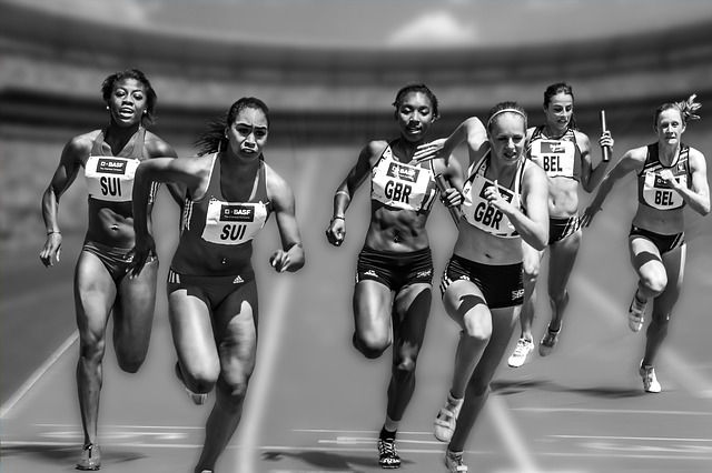 Female runners competing in a track and field relay race, focused and in motion.